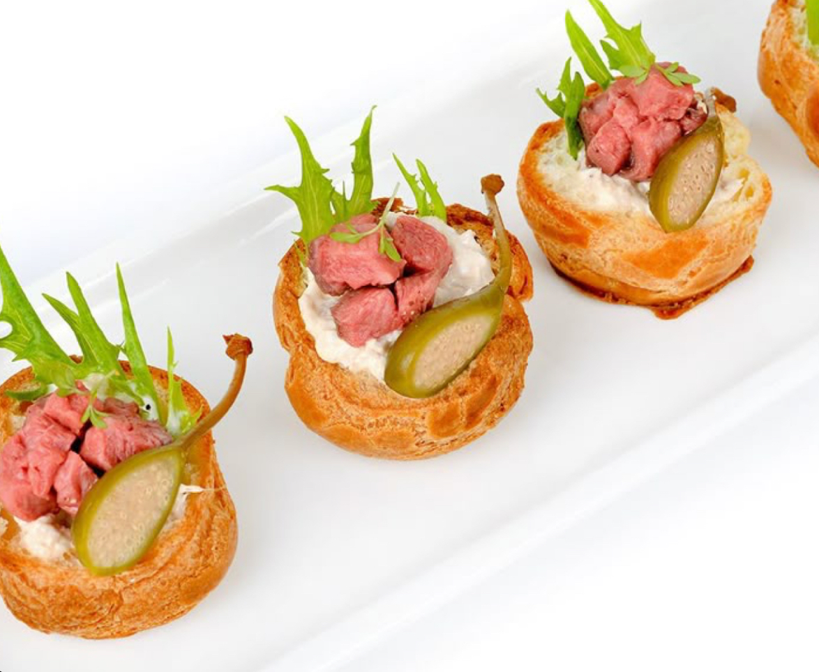 Flaky pastry topped with beef tartare and pickled garnish.
